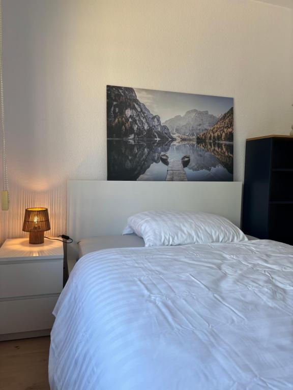 a bedroom with a white bed with a painting on the wall at Comfortable Private Room in a Prime Location! HBF in Wolfsburg