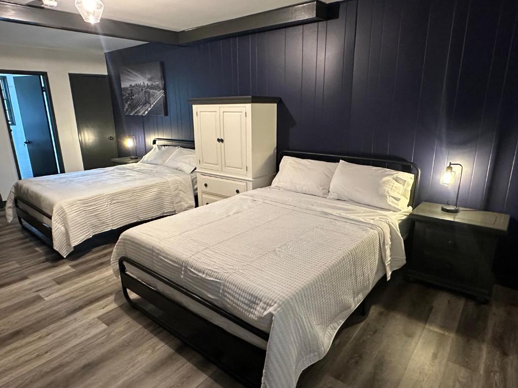 a bedroom with two beds and a blue wall at Keyes Motel in Arlington Heights