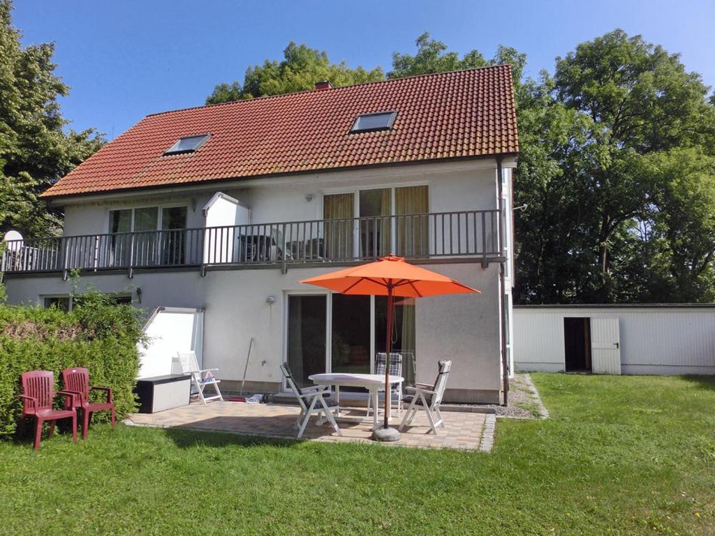 a house with a table and chairs and an umbrella at Fährhof 6b EG in Wiek auf Rügen