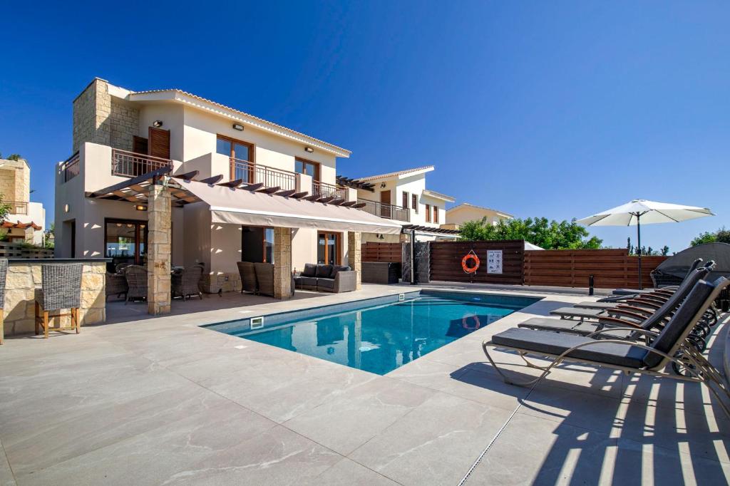 a villa with a swimming pool and some chairs at Modern Villa HG08 Pyrinas with Amazing Golf Views, in heart of Aphrodite Hills in Kouklia