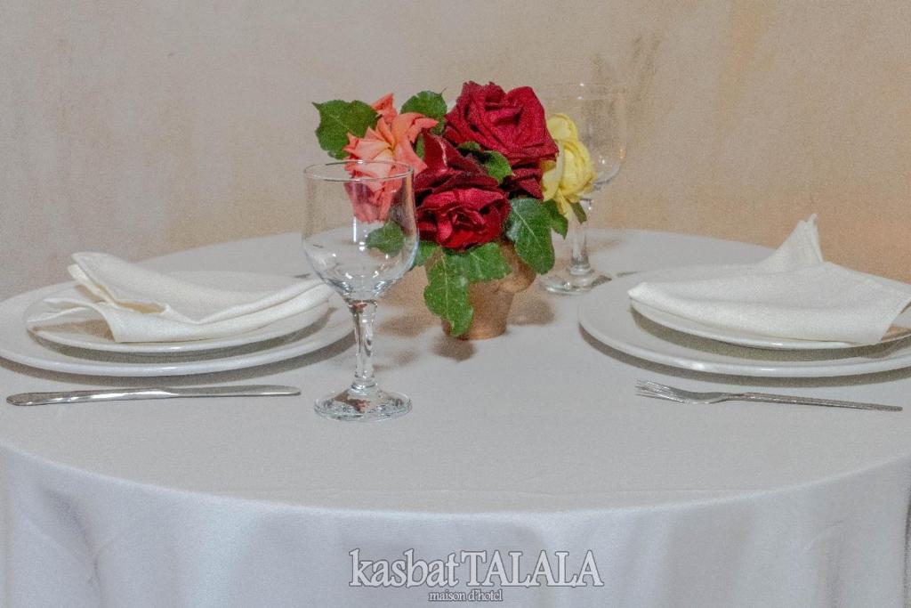 Ein weißer Tisch mit Tellern und einer Vase mit Blumen in der Unterkunft Alkhayer 2 in Tazzarine