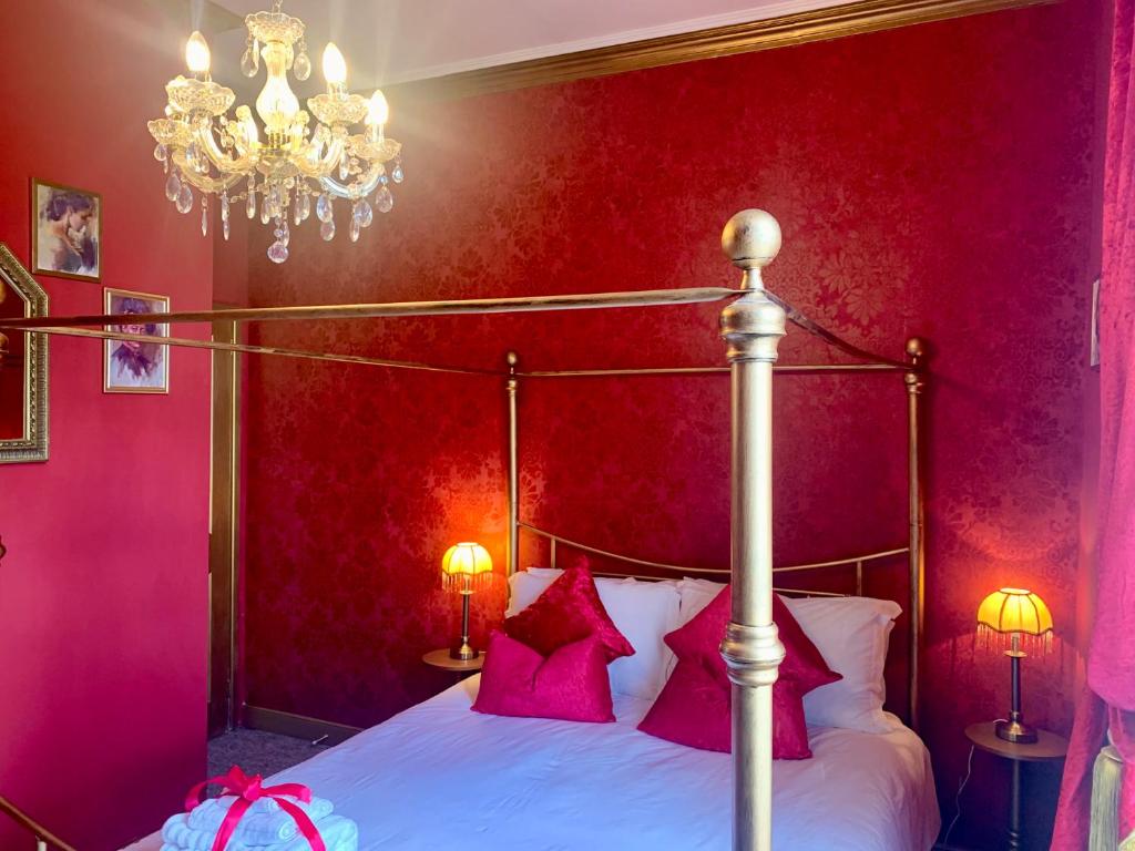 a bedroom with a bed with pink walls and a chandelier at Downton I in Alnwick