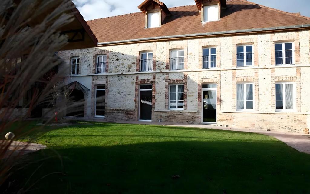 a large brick house with a lawn in front of it at Gîte De La Crayère in Gionges