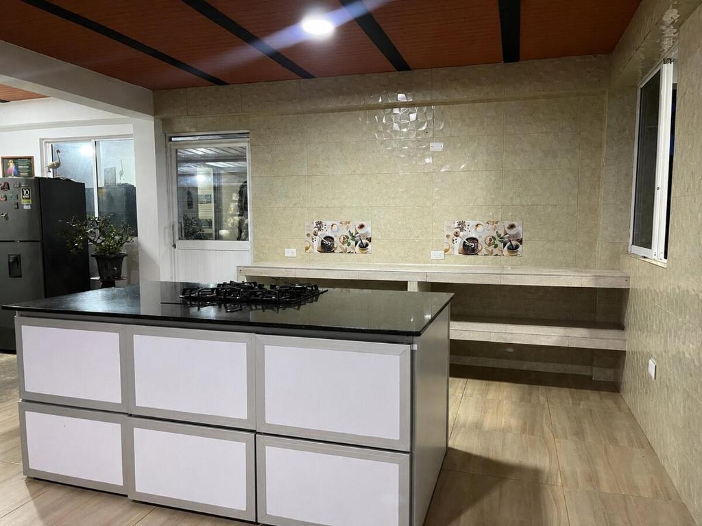 a kitchen with white cabinets and a black counter top at Casa Hotel Villa María - Apia in Apía