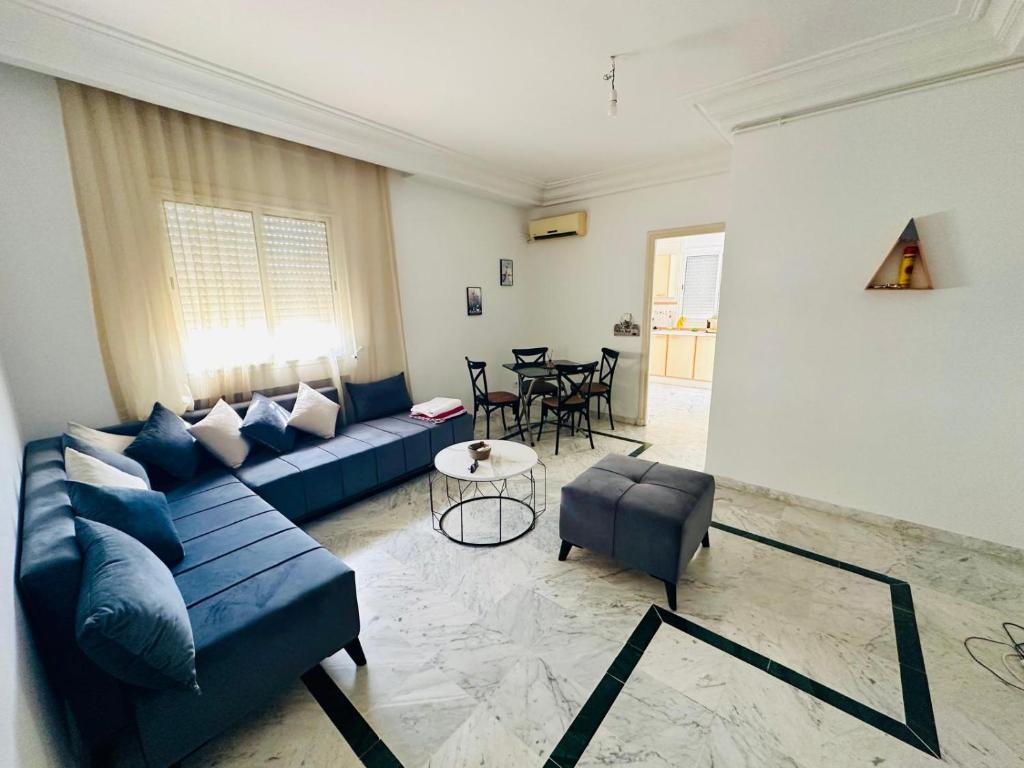 a living room with a blue couch and a table at Eden Cozy Airport in El Aouina Station
