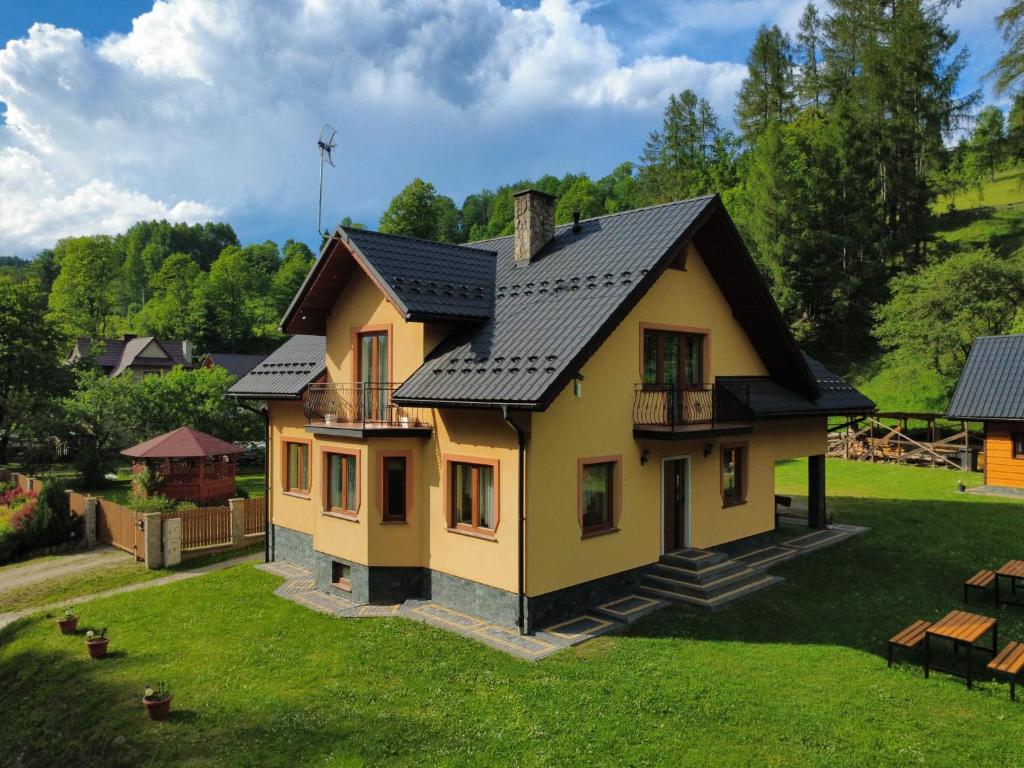 a small yellow house with a black roof at Gościnne Pieniny Pensjonat in Jaworki