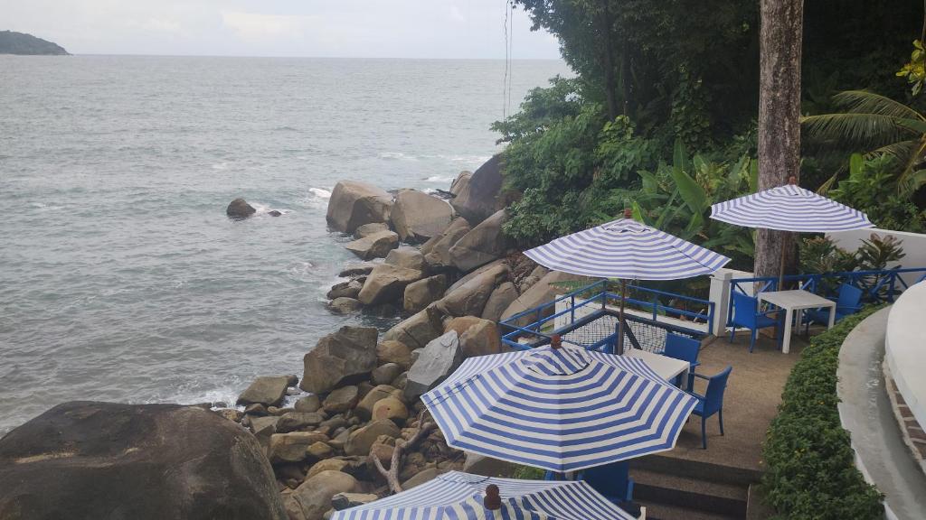 a group of chairs and umbrellas next to the ocean at EnDanni homestay in Phuket