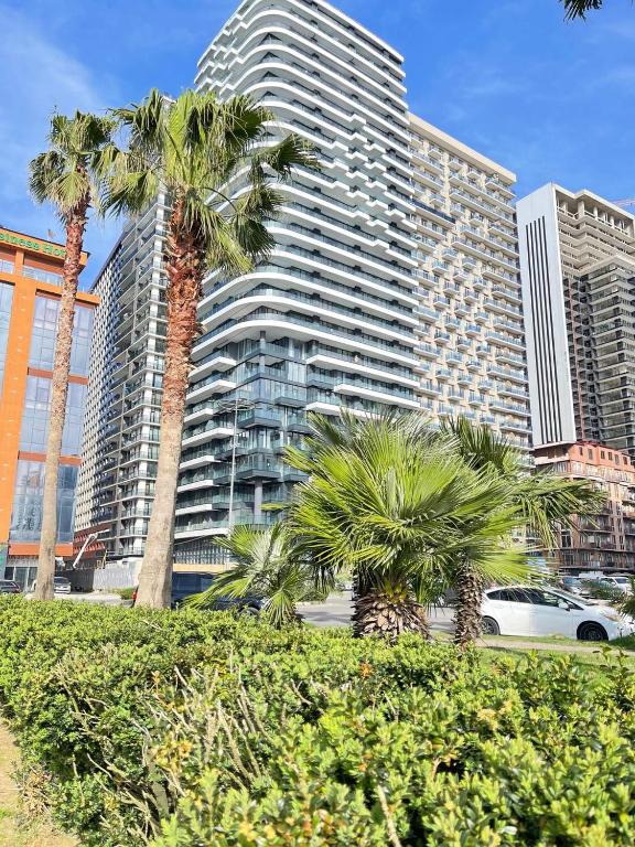 a tall building with palm trees in front of it at Paradise Apartments Solis in Batumi