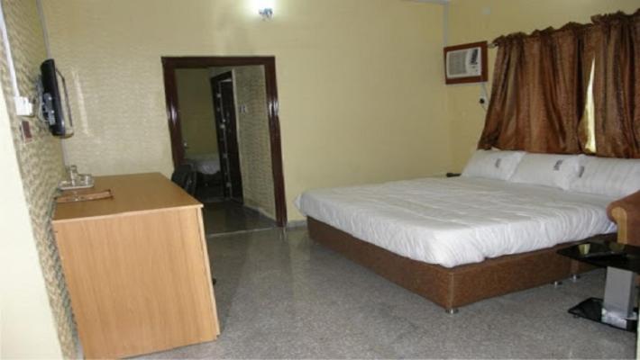 una camera da letto con un letto, una scrivania e una televisione di Agate Hotel a Festac Town