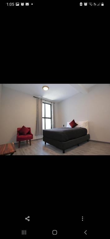 a bedroom with a bed and a red chair at Lailinn Serenity in Santa Cruz Xoxocotlán