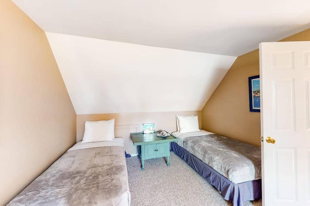 two beds in a small room with a table at Dog-friendly, bayfront home w/rocky beach, full kitchen, washer/dryer & firepit in Gouldsboro