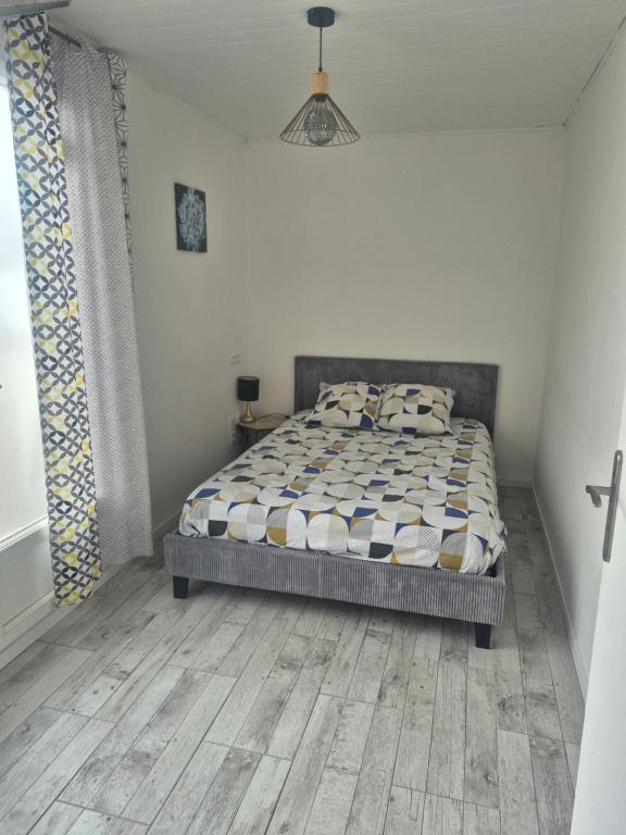 a bedroom with a bed and a wooden floor at Agréable studio indépendant in Froidfond