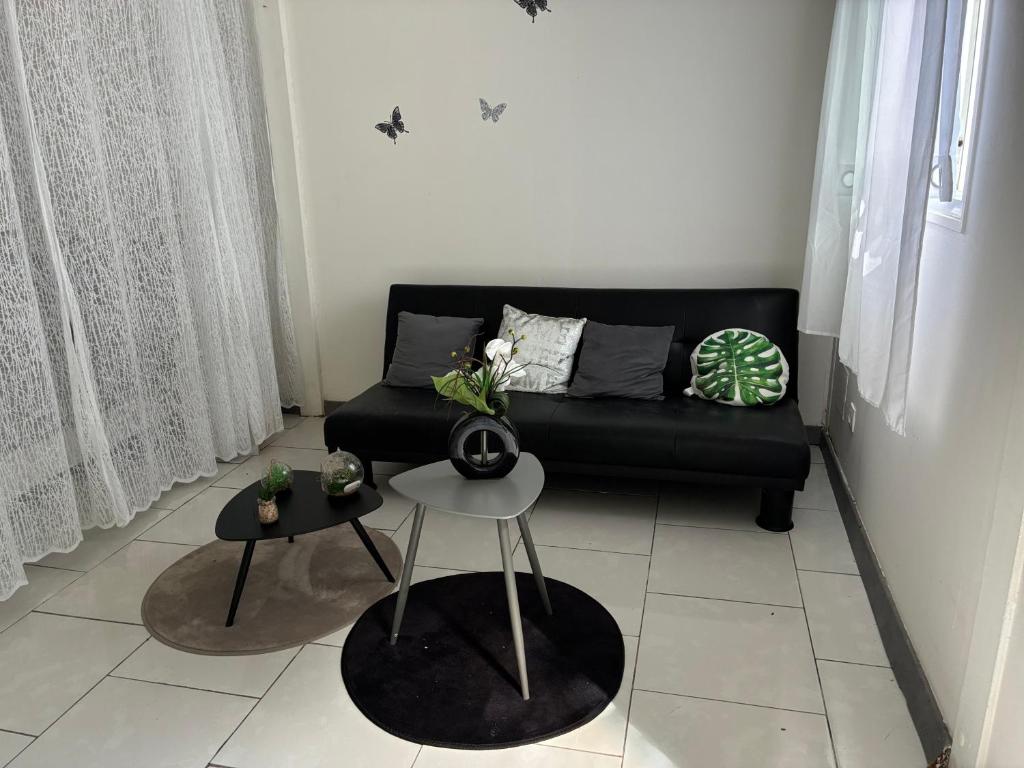 a living room with a black couch and a table at Éclat doasis in Vieux-Habitants