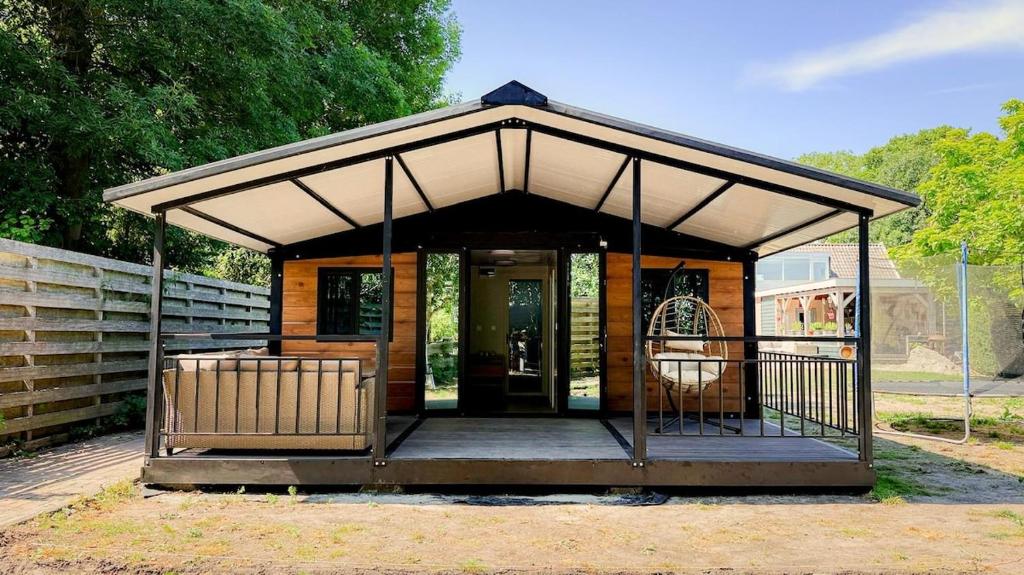 a small house with a roof with a porch at Chalet met grote tuin en privé jacuzzi in Wijdenes