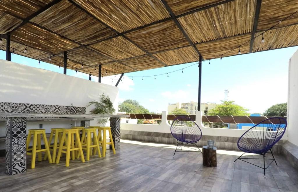 a patio with chairs and a bar on a roof at Valentina Suites by Las Flores Vacation Rentals in Playa del Carmen
