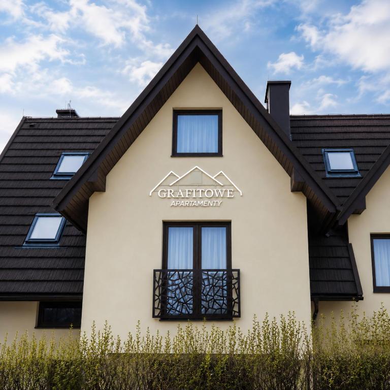 a white house with a black roof at Grafitowe Apartamenty in Czarna Góra