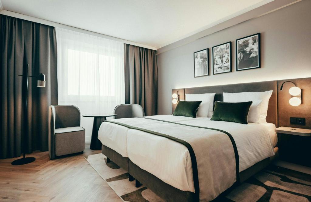 a hotel room with a large bed and a desk at Leonardo Hotel Köln in Cologne