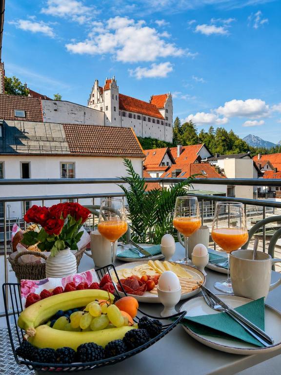 a table with a plate of food and glasses of orange juice at Schwanstein Apartments Füssen ZENTRUM in Füssen