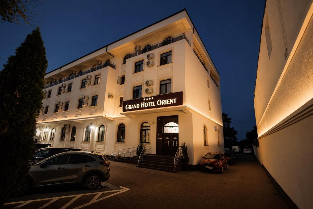 ein weißes Gebäude mit einem davor geparkten Auto in der Unterkunft Grand Hotel Orient Braila in Brăila