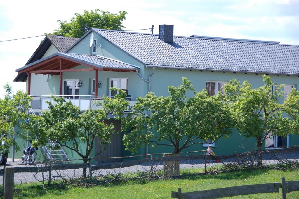 uma casa azul com árvores em frente em Gänschen klein em Ellscheid