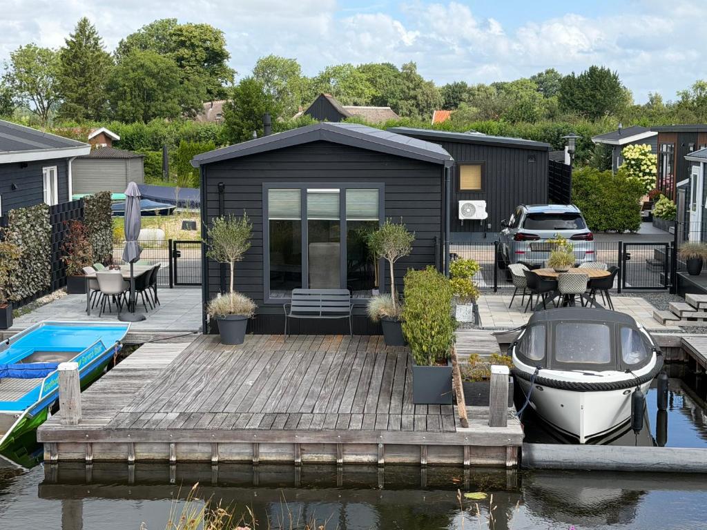 a black tiny house with a boat on a dock at Luxe Chalet San Marco in Giethoorn
