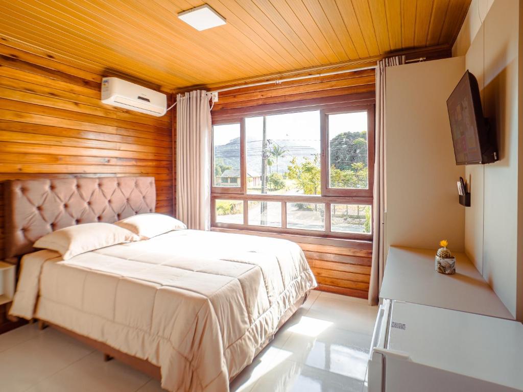 a bedroom with a bed and a large window at Hotel pousada BR 285 in Turvo