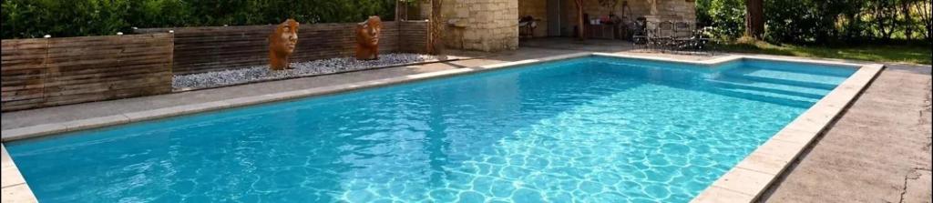 a swimming pool with blue water in a yard at VILLA LES HAUTS VALLONS in Puylaroque