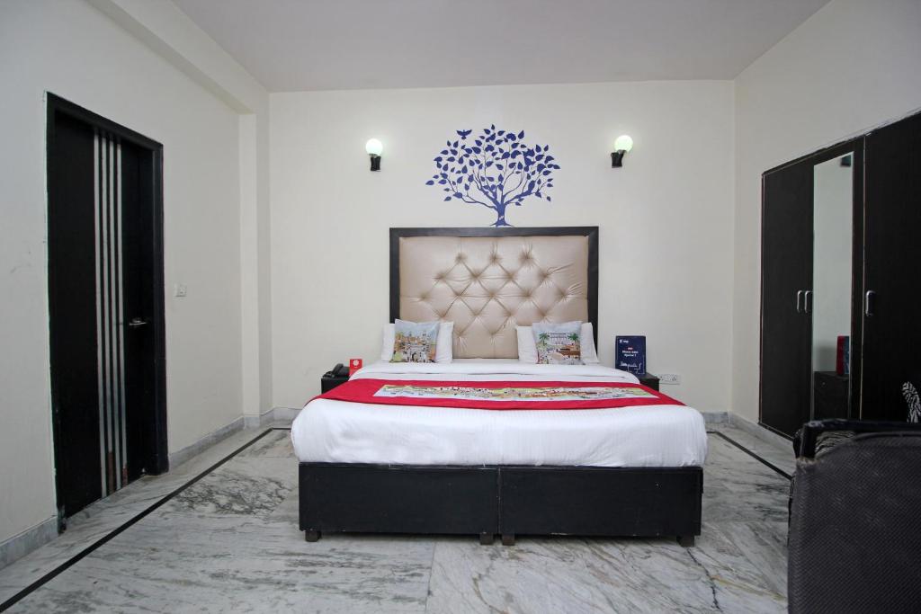 a bedroom with a large bed with a tree on the wall at Hotel O Staysnap in Indirapuram
