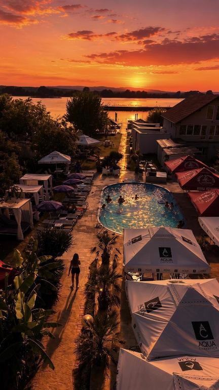 a resort with two pools and umbrellas at sunset at ElGringo Clisura Dunarii in Moldova Nouă