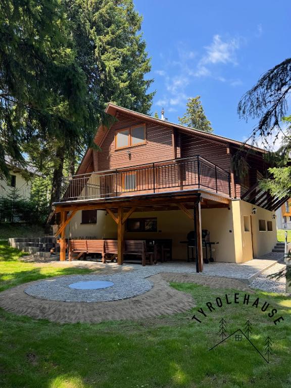 a large wooden house with a balcony and a yard at Chata - TYROLEHAUSE in Martin