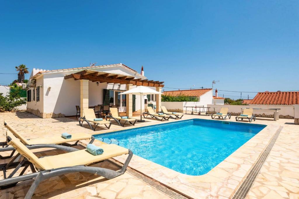 a villa with a swimming pool and patio furniture at Villa Ingrid Porter by Villa Plus in Cala en Porter