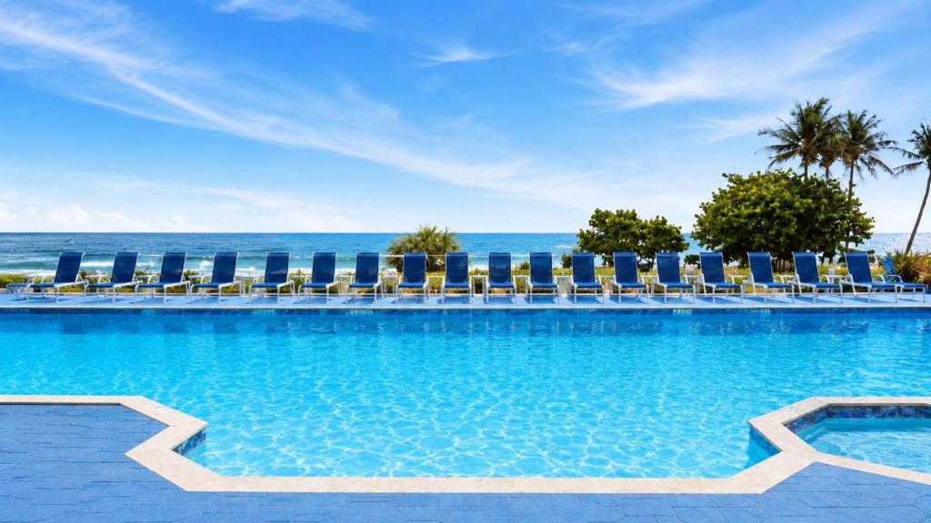 a pool with chairs and the ocean in the background at Hollywood Beach Tower in Hollywood