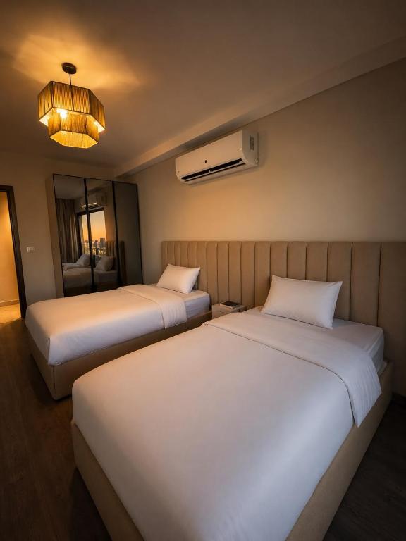 two beds in a hotel room with a chandelier at ZED Towers City View Apartment in Sheikh Zayed