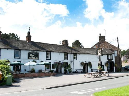 a white building with picnic tables in front of it at The Boot and Shoe in Greystoke