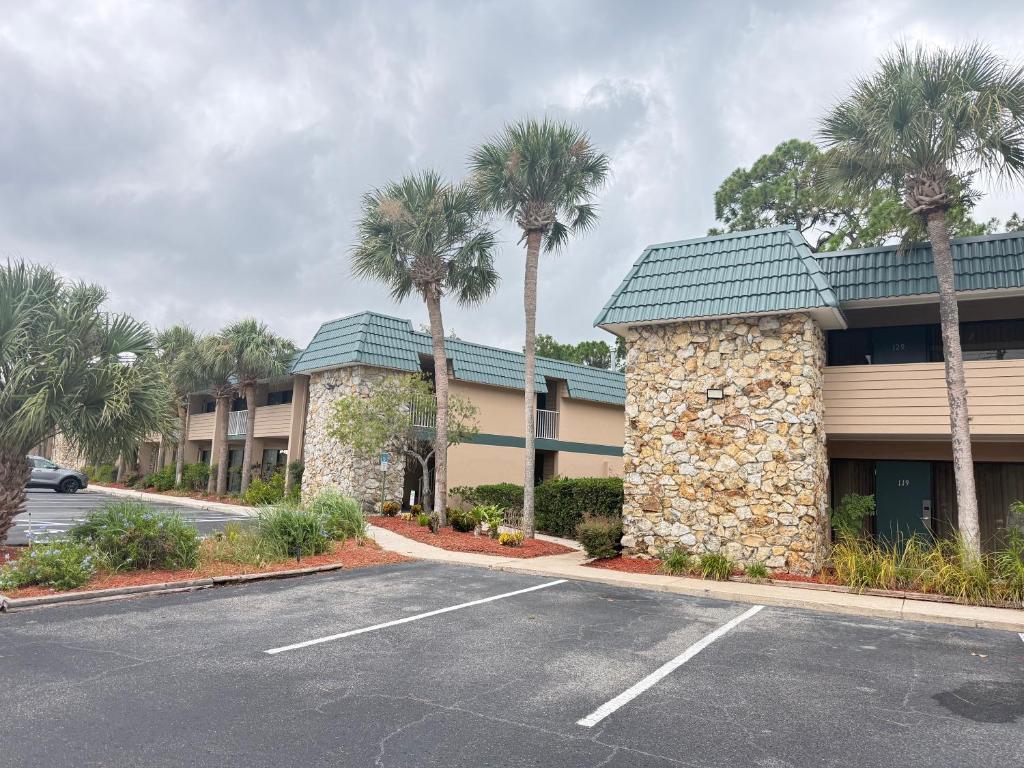 a parking lot in front of a hotel with palm trees at Lifetime of Vacations in Orlando