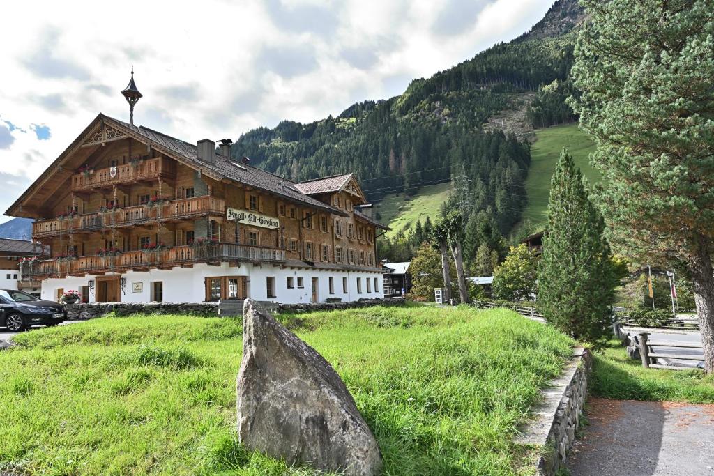 a large wooden building in a field with a rock at Ferienwohnungen Altginzling in Ginzling