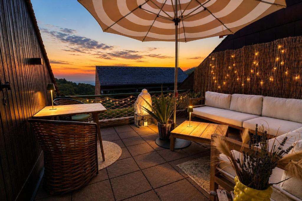 a patio with a couch and an umbrella and a table at Schwarzwaldloge Zeitlos in Sasbachwalden