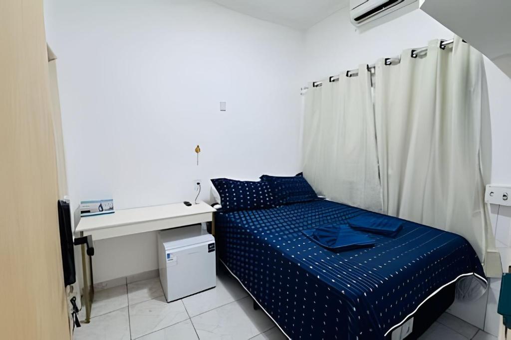 a small bedroom with a bed and a desk at Abaíra Serra Azul Suítes 04 - Centro in Petrolina