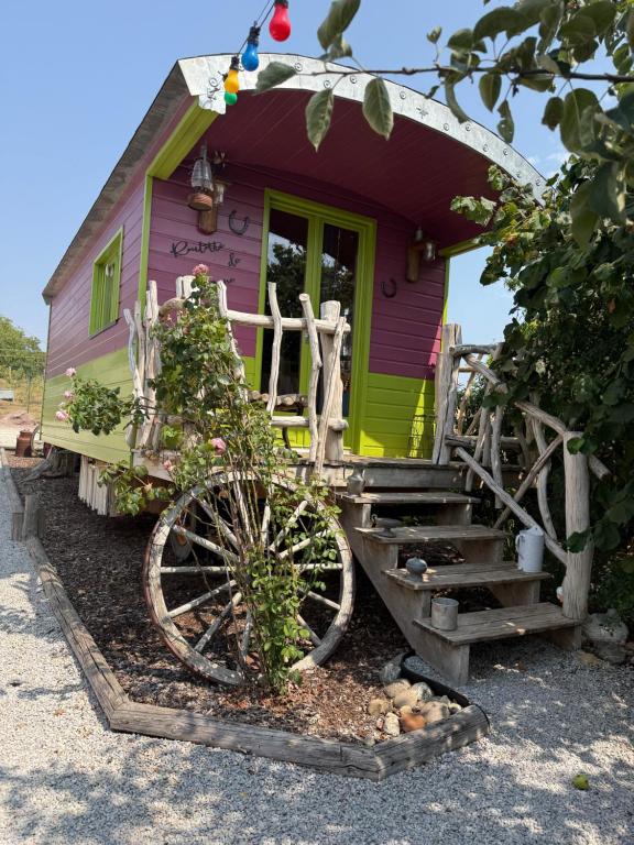 a purple and green house with a wheel in front of it at Roulotte de Charme in Bréconchaux