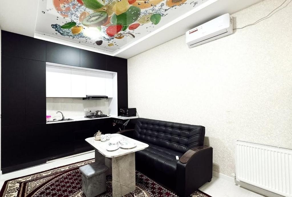a living room with a black leather couch and a table at ARZON Mehmonxona in Tashkent