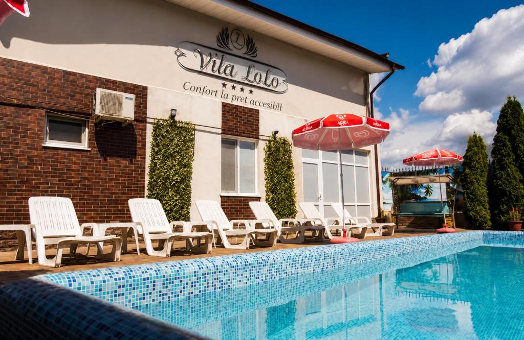 a pool with chairs and umbrellas in front of a hotel at Vila LOLO in Chişinău