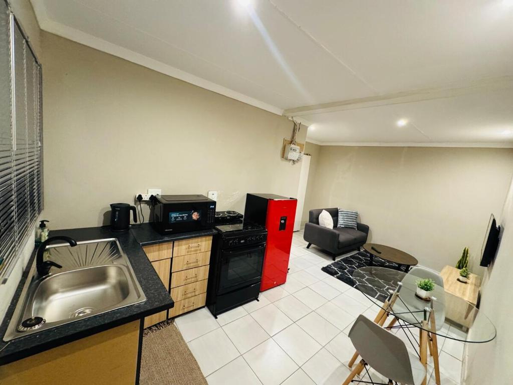 a kitchen with a sink and a red refrigerator at Hei Stays One Bed Apartment in Bronkhorstspruit