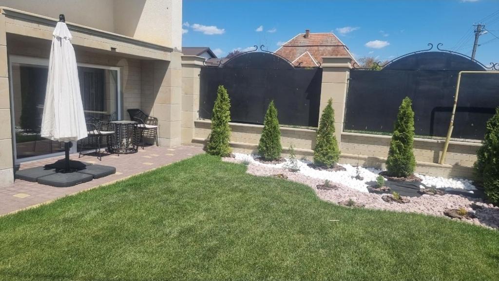 a backyard with a lawn and a white umbrella at Гостинний дім in Shom