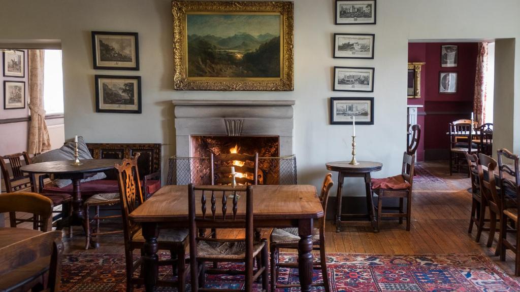a dining room with a fireplace and a table and chairs at The Derby Arms in Grange Over Sands