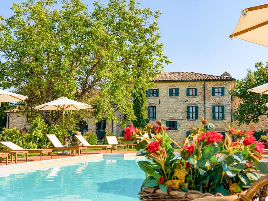 a swimming pool with chairs and flowers and a building at I Costanti in Caldiero