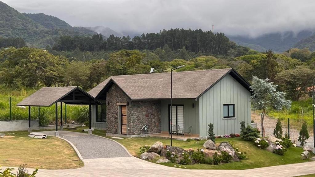 a small house in a field with mountains in the background at Retreat Boquete Cabins in Bajo Boquete
