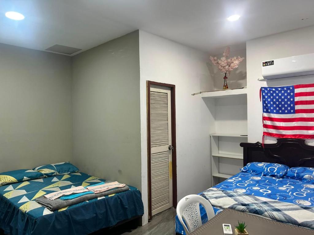 a bedroom with two beds and an american flag on the wall at Hospedaje Blue House - Consulado americano - Habitacion 2 in Guayaquil