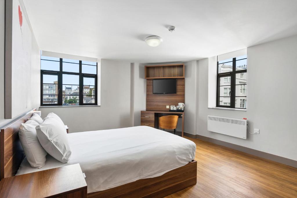 a bedroom with a bed and a desk and windows at The Mitre Hotel Brighton in Brighton & Hove