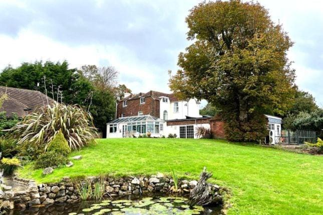 a house with a pond in front of a yard at 5-bed house with indoor pool, Jacuzzi &Downs views in Herstmonceux