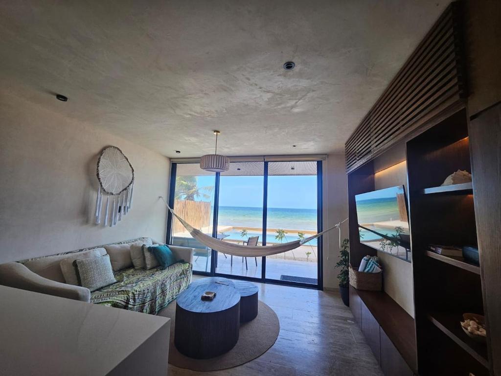 a living room with a hammock in front of the ocean at Beachfront , alberca y terraza in Telchac Puerto